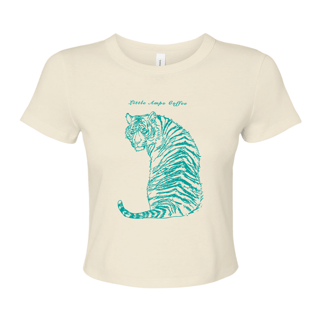 An off-white short-sleeve crop top t-shirt featuring a teal graphic of a sitting tiger with the text 'Little Amps Coffee"