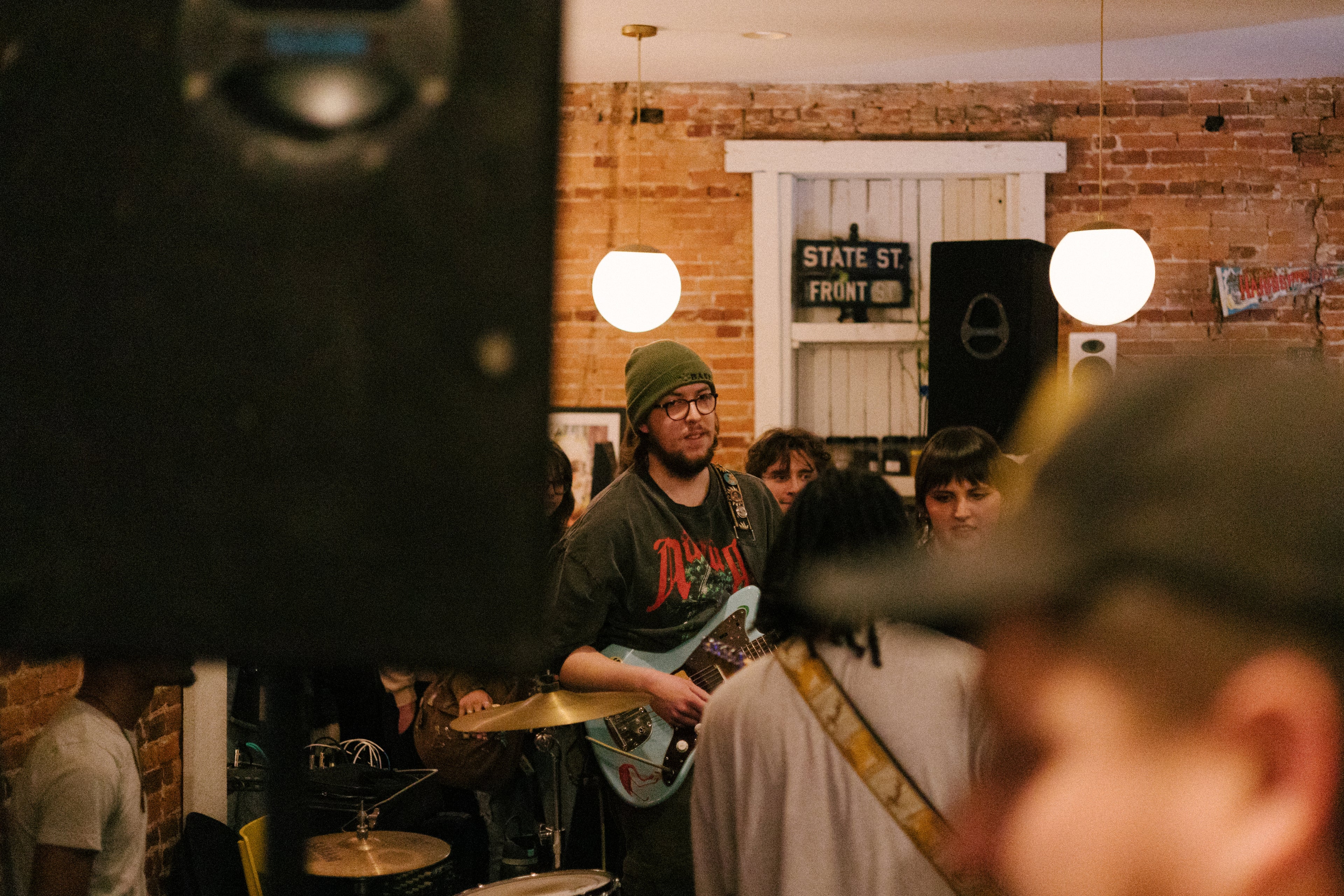 Person playing guitar in a coffee shop with brick walls